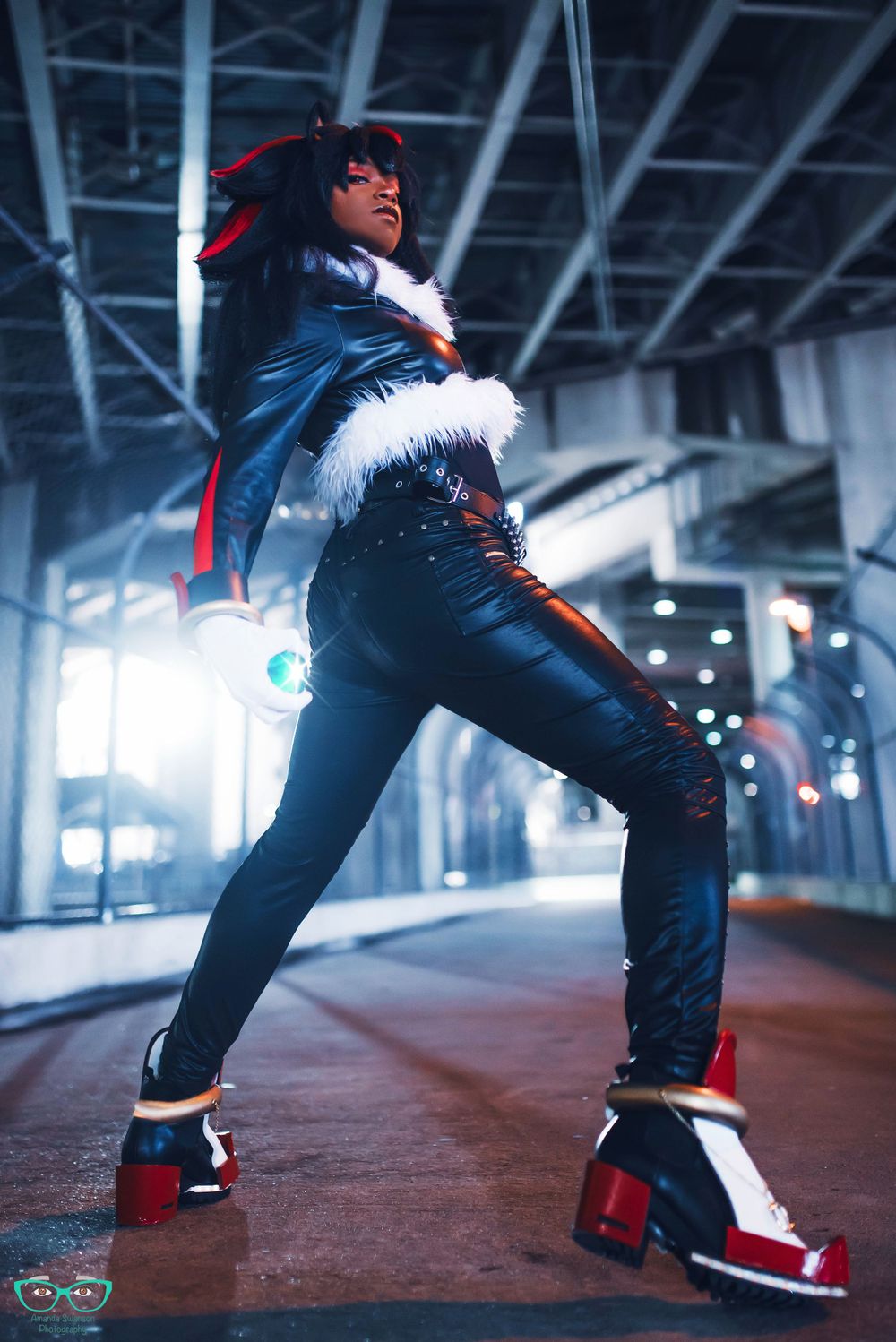 A cosplayer strikes a dynamic pose in a blue and white costume with red accents.