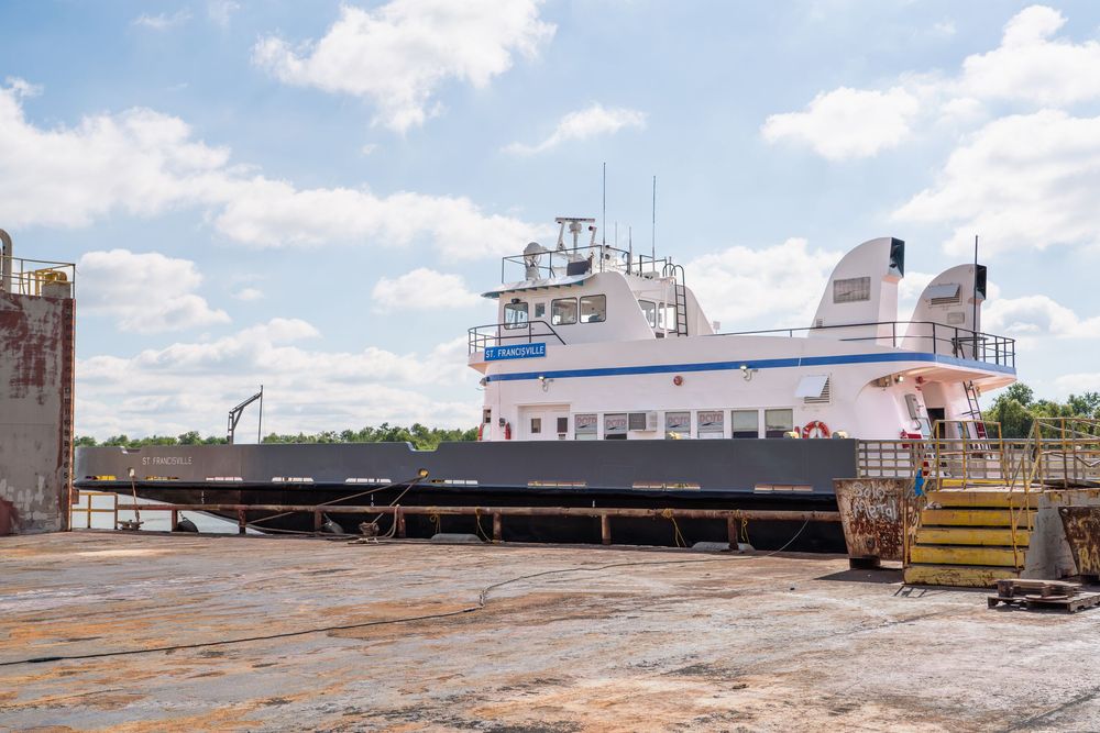 Large industrial vessels and boats docked at a commercial shipyard with cloudy sky overhead.