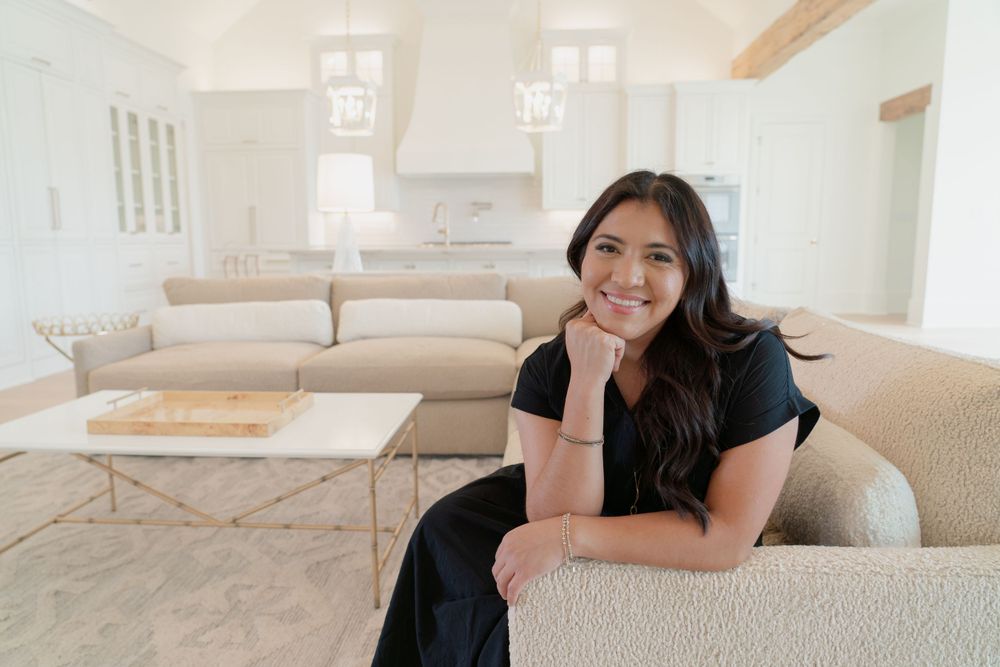 A person relaxing on a beige couch in a bright modern living room with natural lighting.