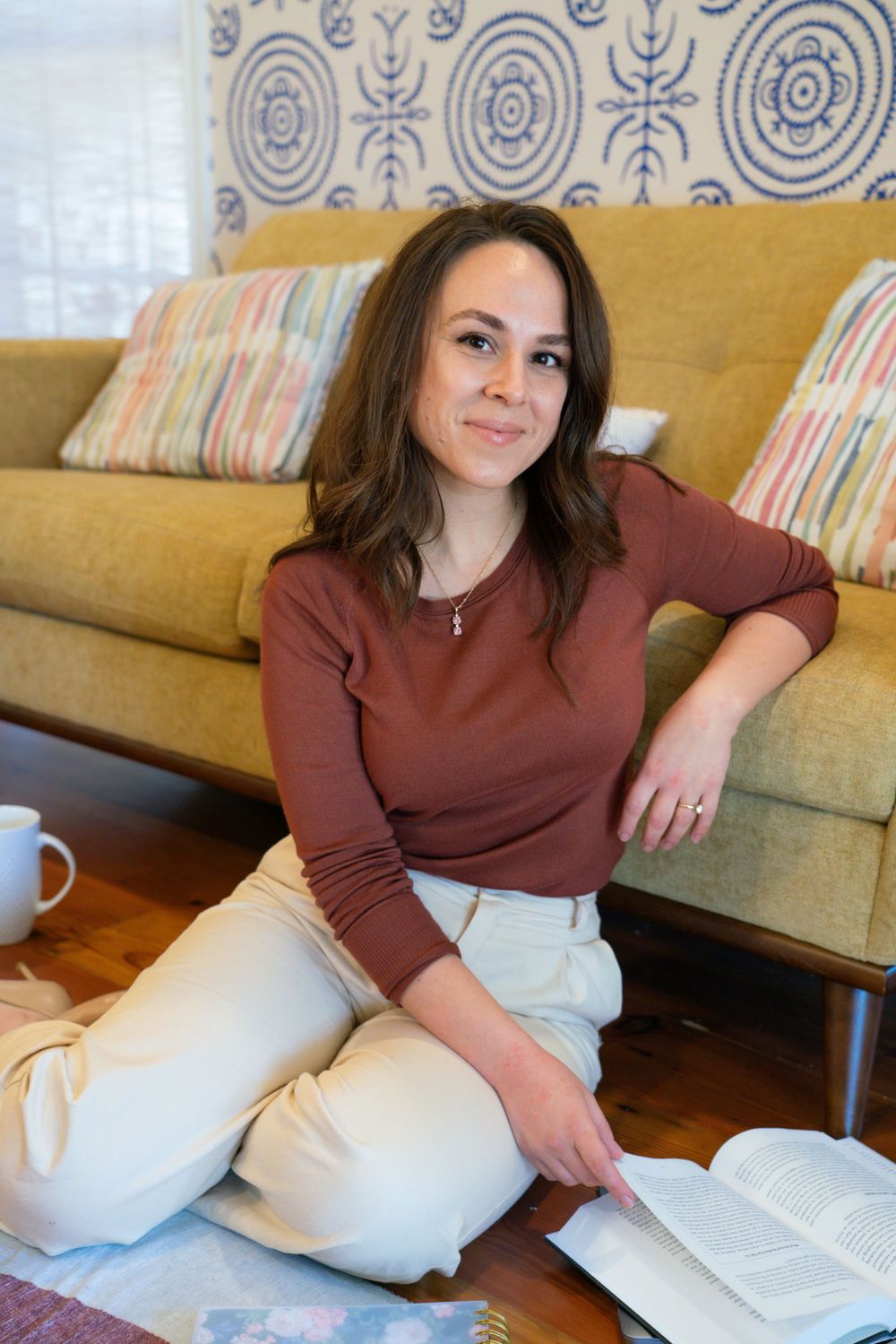 A person relaxes on a yellow couch with decorative pillows while reading.