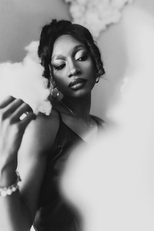 Black and white portrait of an elegant woman with glam makeup, pearl bracelet, and updo hairstyle posing gracefully.