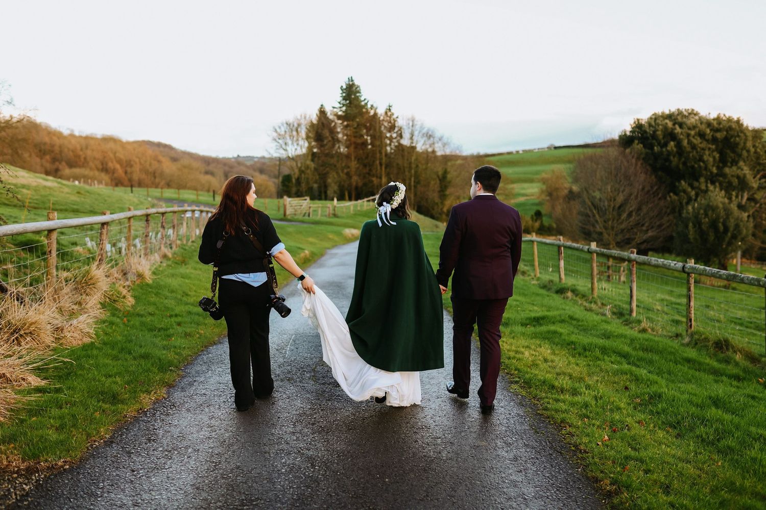 Wedding party walking along a scenic countryside path surrounded by rolling hills.