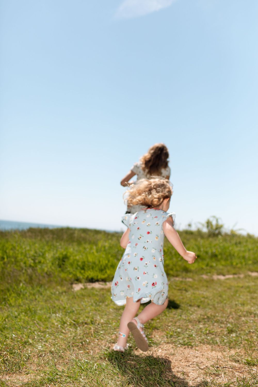 A child in a floral dress twirls freely in a sunny meadow.