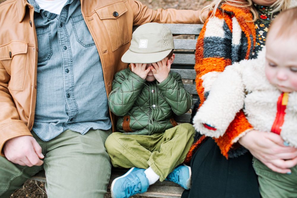 Three people sitting together on outdoor furniture in casual winter clothing.