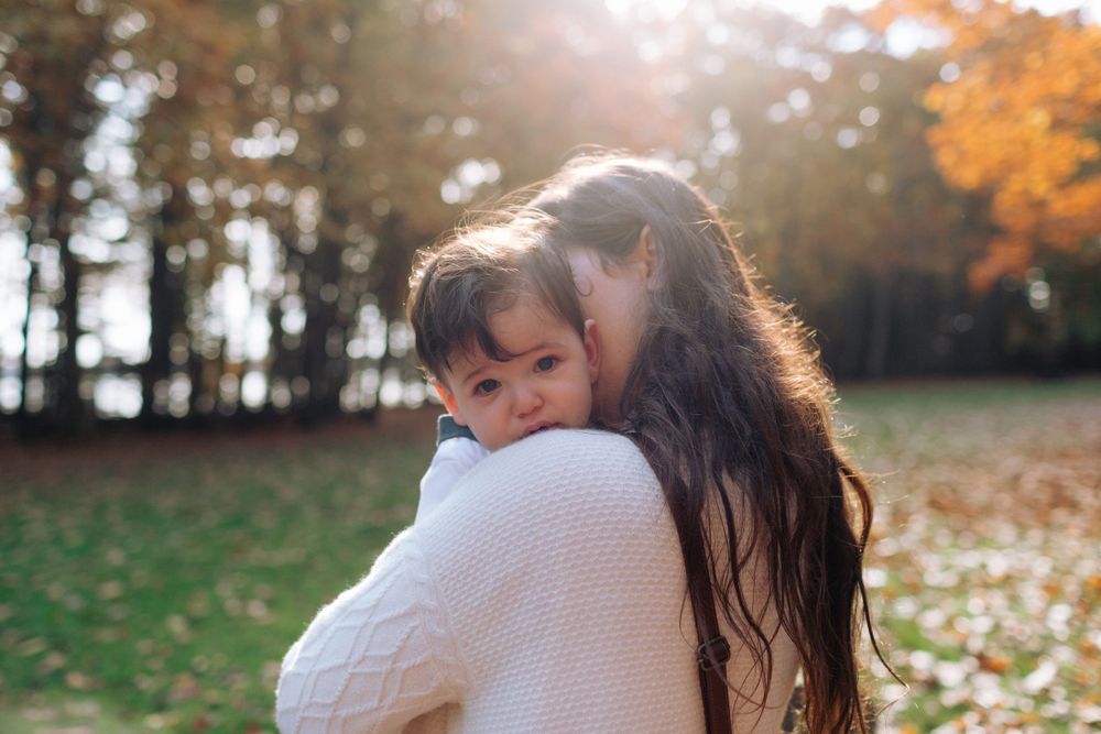 A tender autumn moment captured in golden sunlight with fall foliage in background.