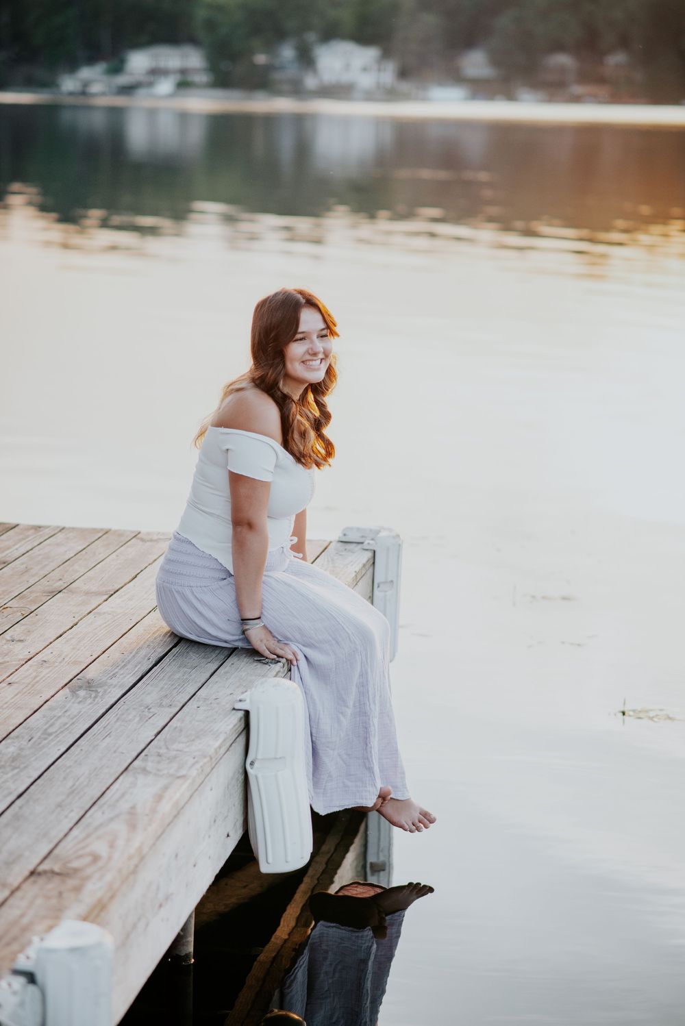 Peaceful lakeside senior portrait on wooden dock during golden hour.