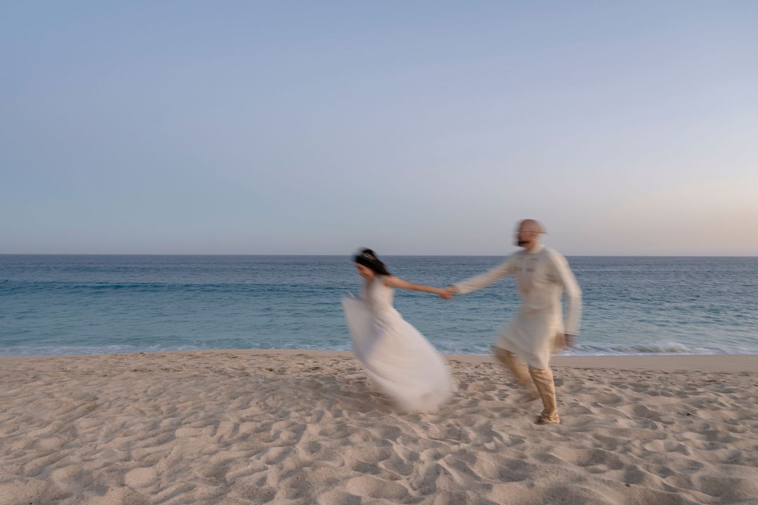 Bride and groom running on beach after ceremony