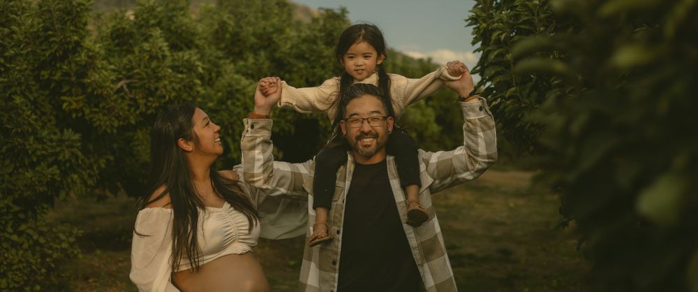 A family laughs together while walking on a path through lush green apple orchard at Los Rios Rancho