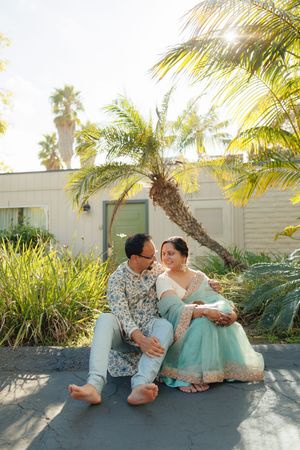 A couple in matching mint green outfits share romantic moments against a tropical garden backdrop with palm trees.