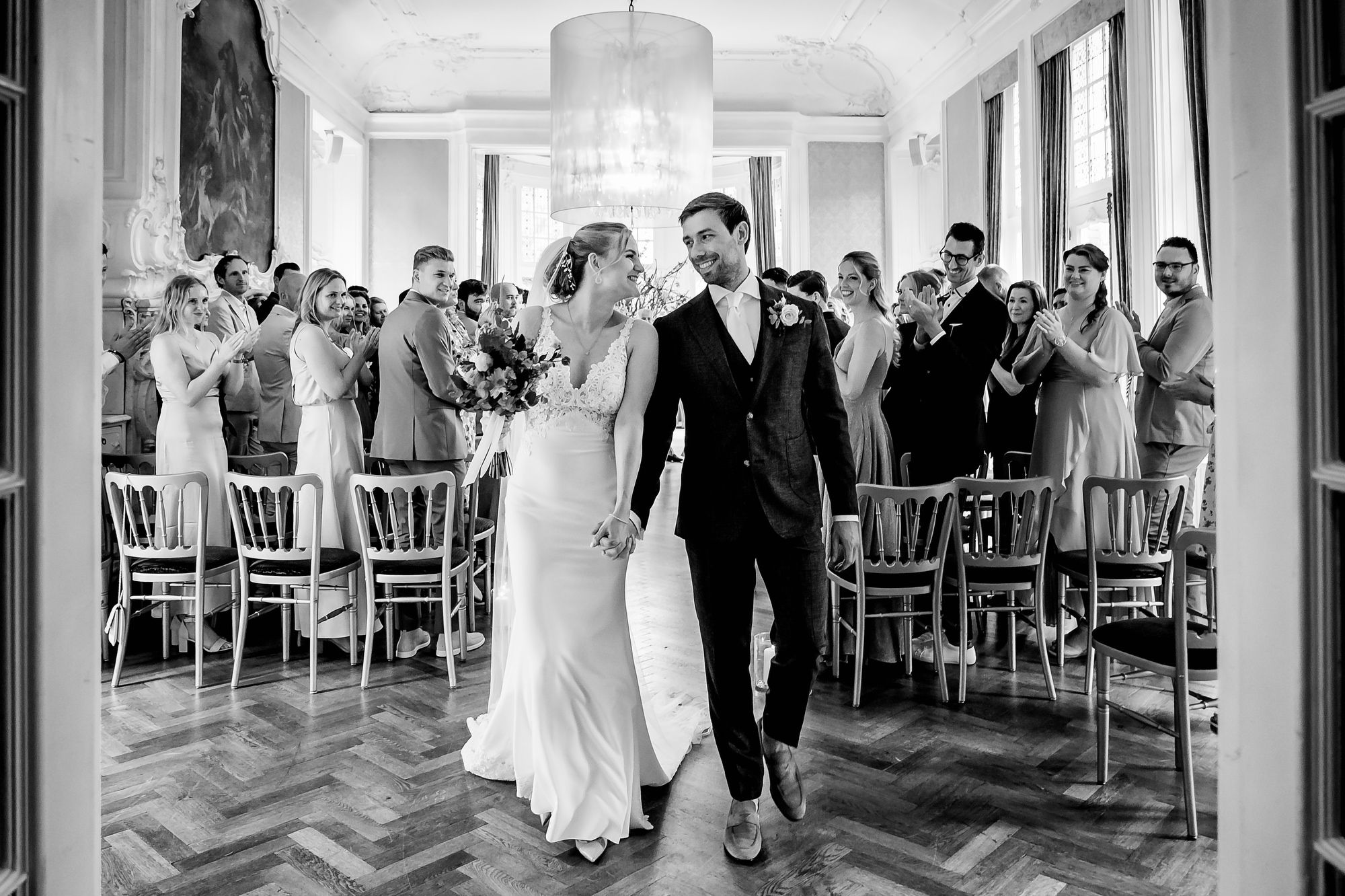 Bride and groom hold hands and look at each other while existing their wedding ceremony location in The Hague.