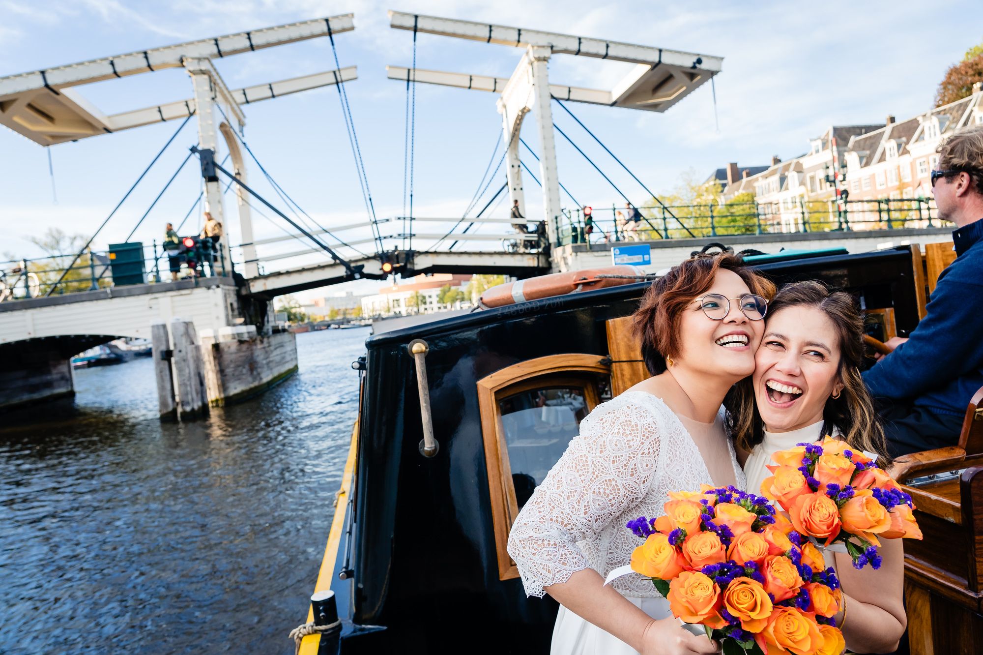 Two brides share a hug and a laugh during a boat ride on their wedding day.