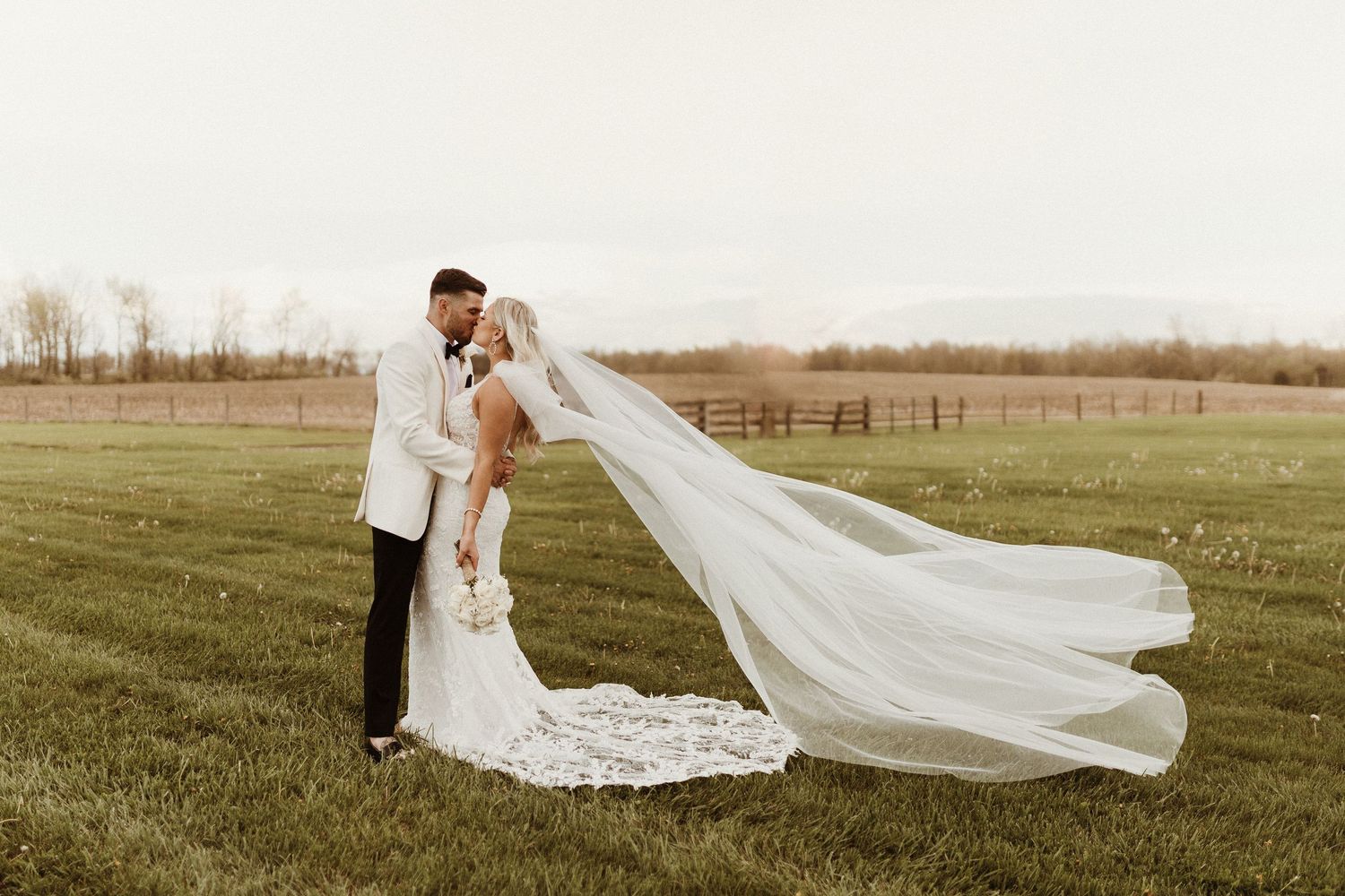 A wedding portrait of a couple kissing, the veil blowing in the wind.