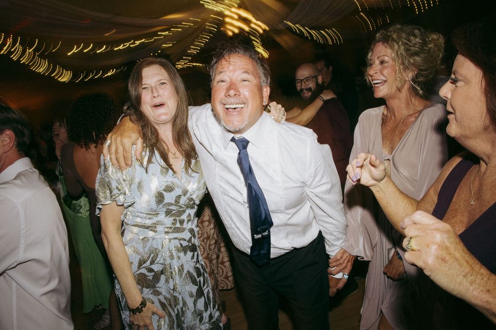 Guests dancing and celebrating on a crowded dance floor at a festive wedding reception party.