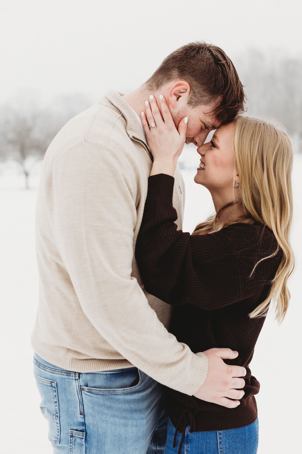 Maine winter engagement session with couple walking through fresh snow in a scenic field