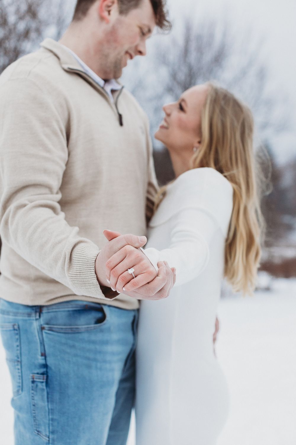 Snowy Maine engagement session with couple kissing under falling snowflakes