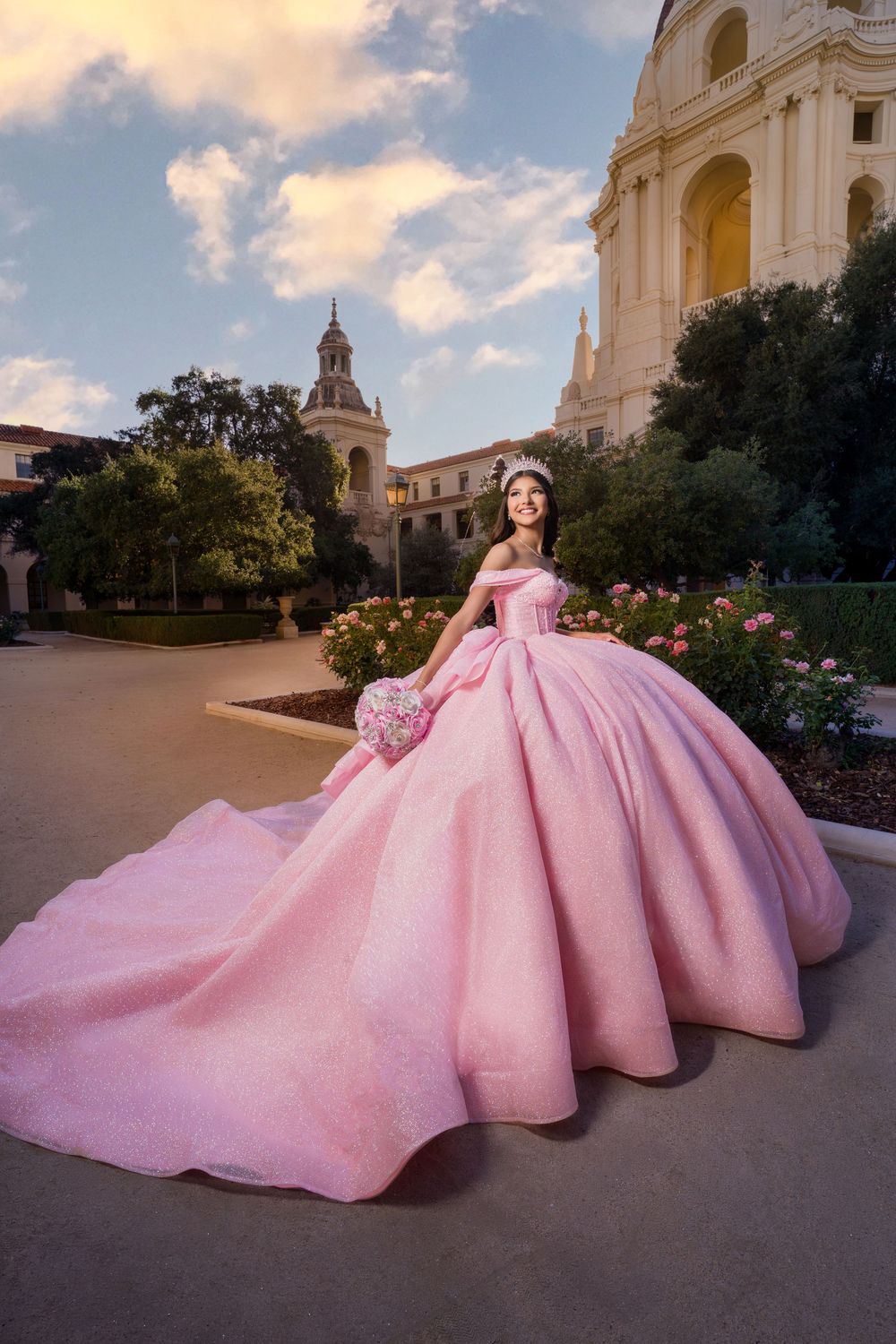 A stunning pink ballgown with a voluminous skirt photographed in front of a grand church building at sunset.