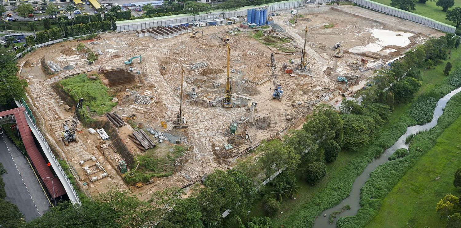 Aerial view of a large construction site with cranes and excavation work surrounded by greenery. Aerial Site Intelligence