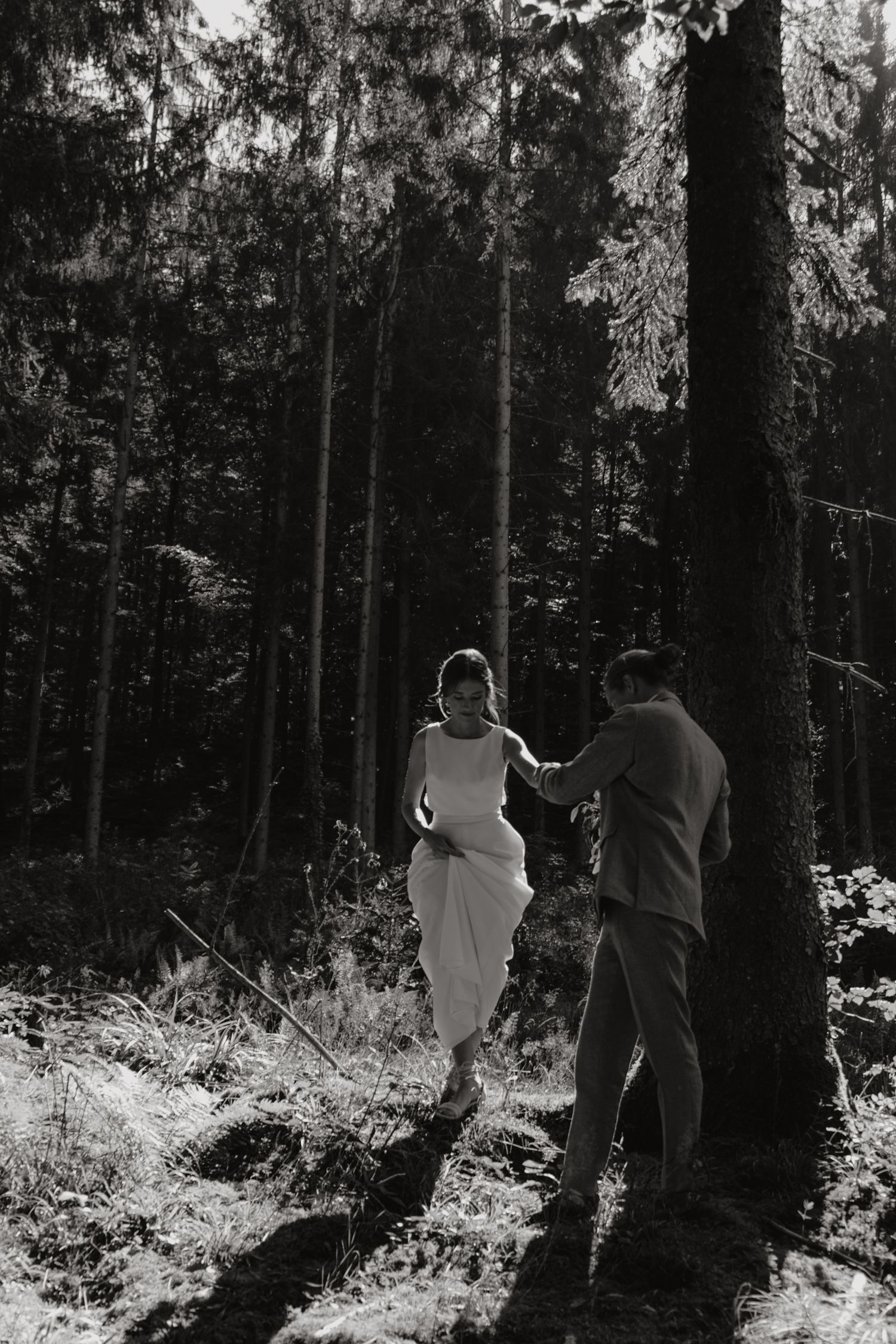 Silhouetted couple exploring a moody forest setting during their wedding photoshoot.