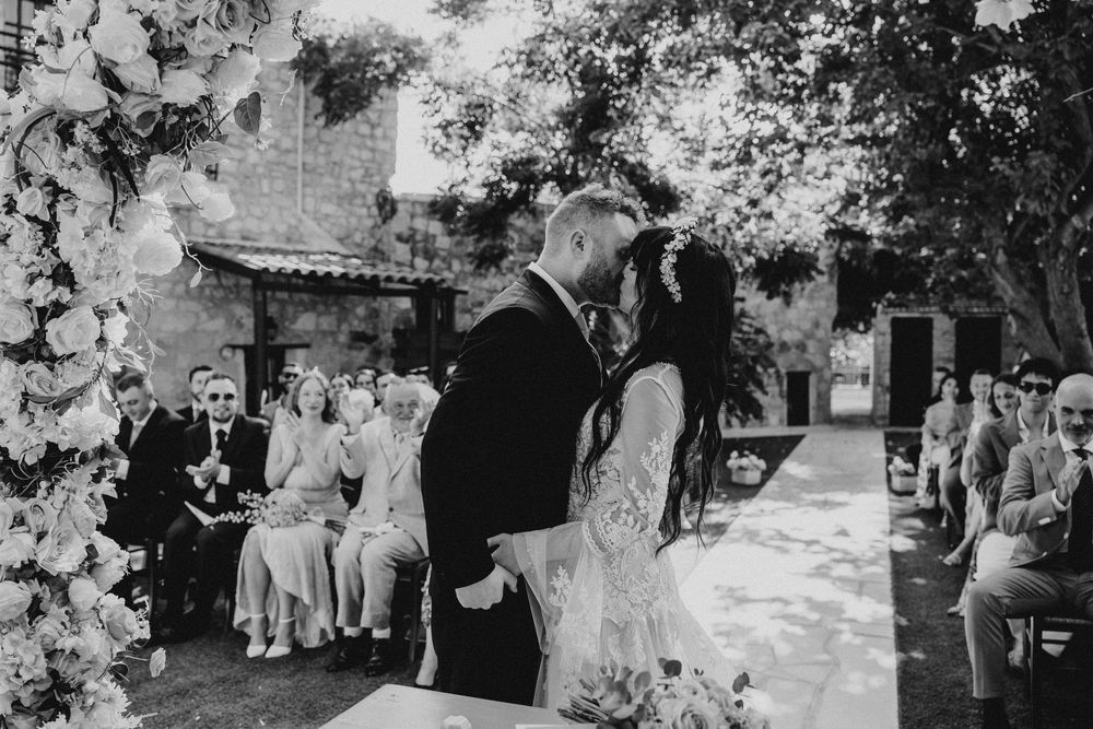 A black and white wedding photo collage showing outdoor ceremony moments and floral decorations at a garden venue.