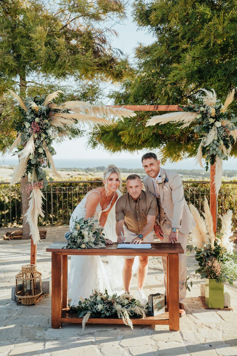 A series of wedding photos showing a couple posing on a rustic wooden bench under trees with decorative floral arrangements.