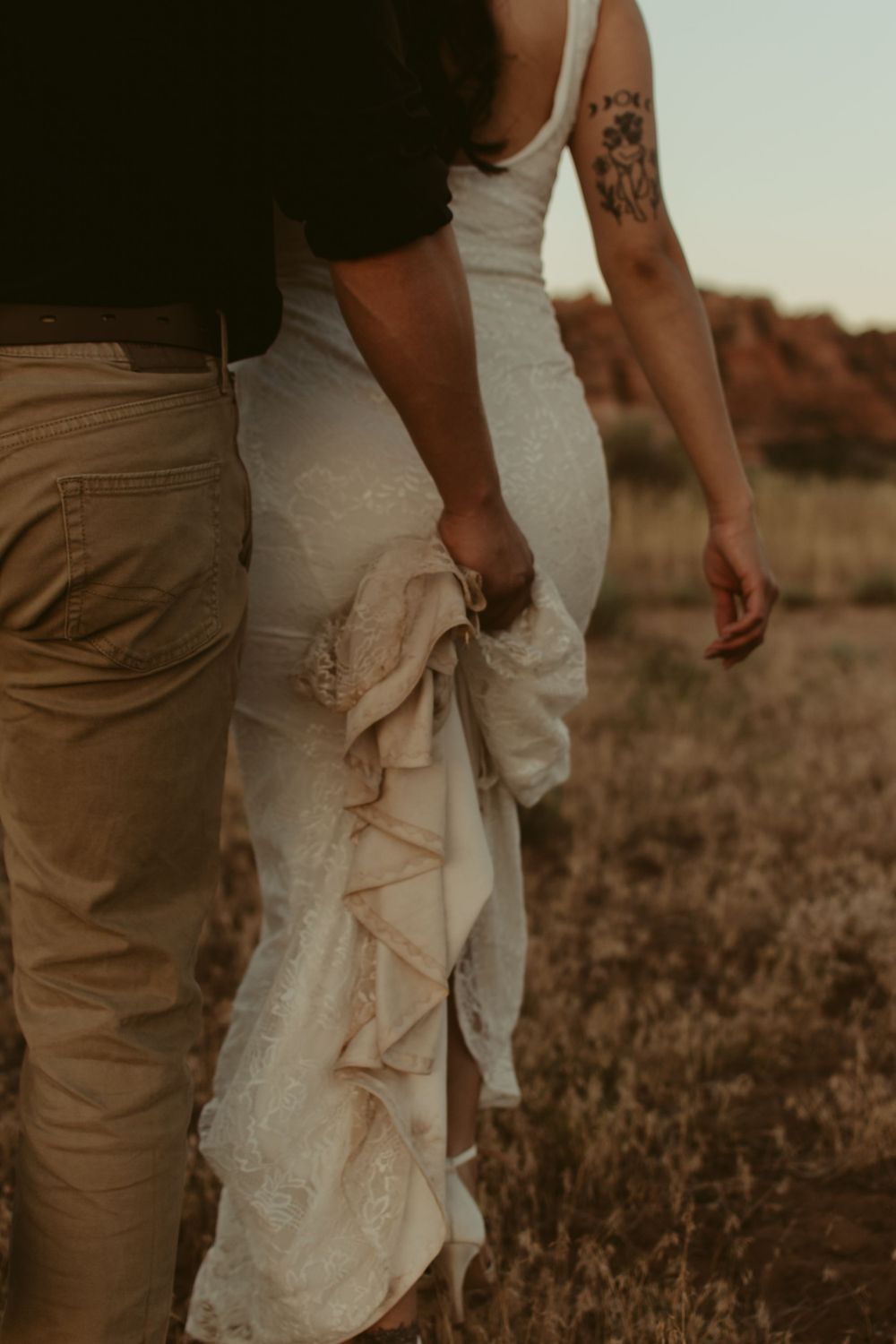 Close-up of people walking through a field at sunset, focusing on their lower bodies.