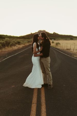 A couple embracing on an empty road during golden hour.