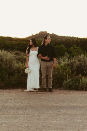 A couple walking together on a desert path during sunset.