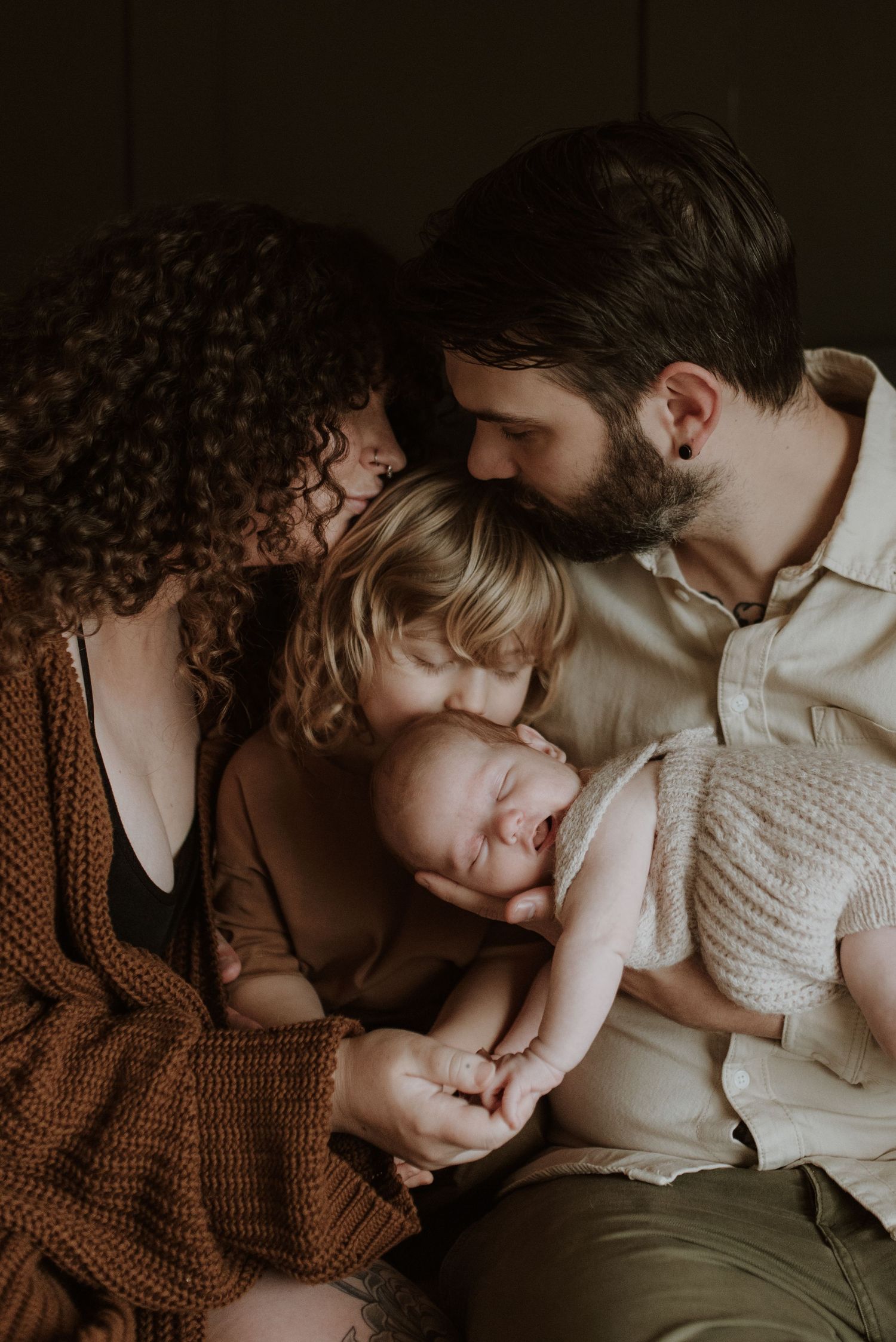 A loving family cradling eacherother and adoringly gazing on their newborn child.
