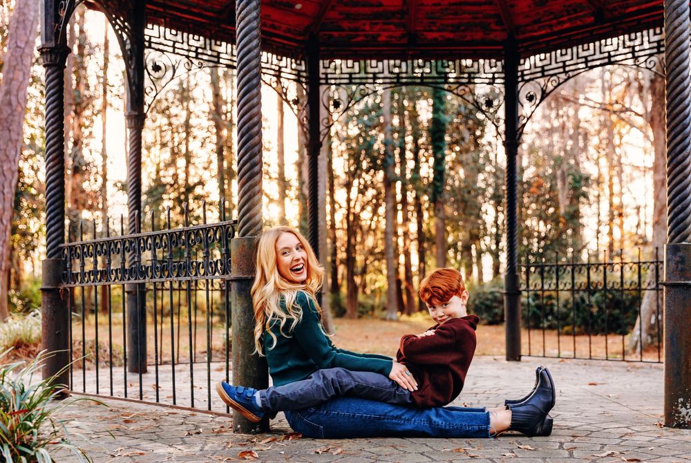 A couple relaxes together on wrought iron steps in a wooded outdoor setting.