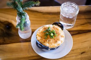 Mac and cheese dish topped with fresh herbs served in a cast iron skillet with a glass of water.