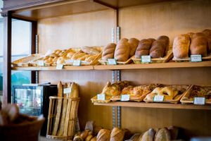 Fresh baked artisanal bread loaves displayed on wooden bakery shelves.