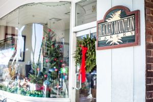 Storefront window decorated for holidays with Rocky Mountain sign and festive wreaths.