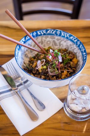 Asian noodle bowl with mixed vegetables and garnishes served with chopsticks.