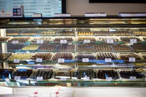 Display case filled with rows of gourmet chocolates and confections.