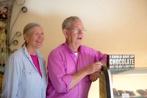 Two people wearing pink shirts share a joyful moment while standing together against a beige wall.