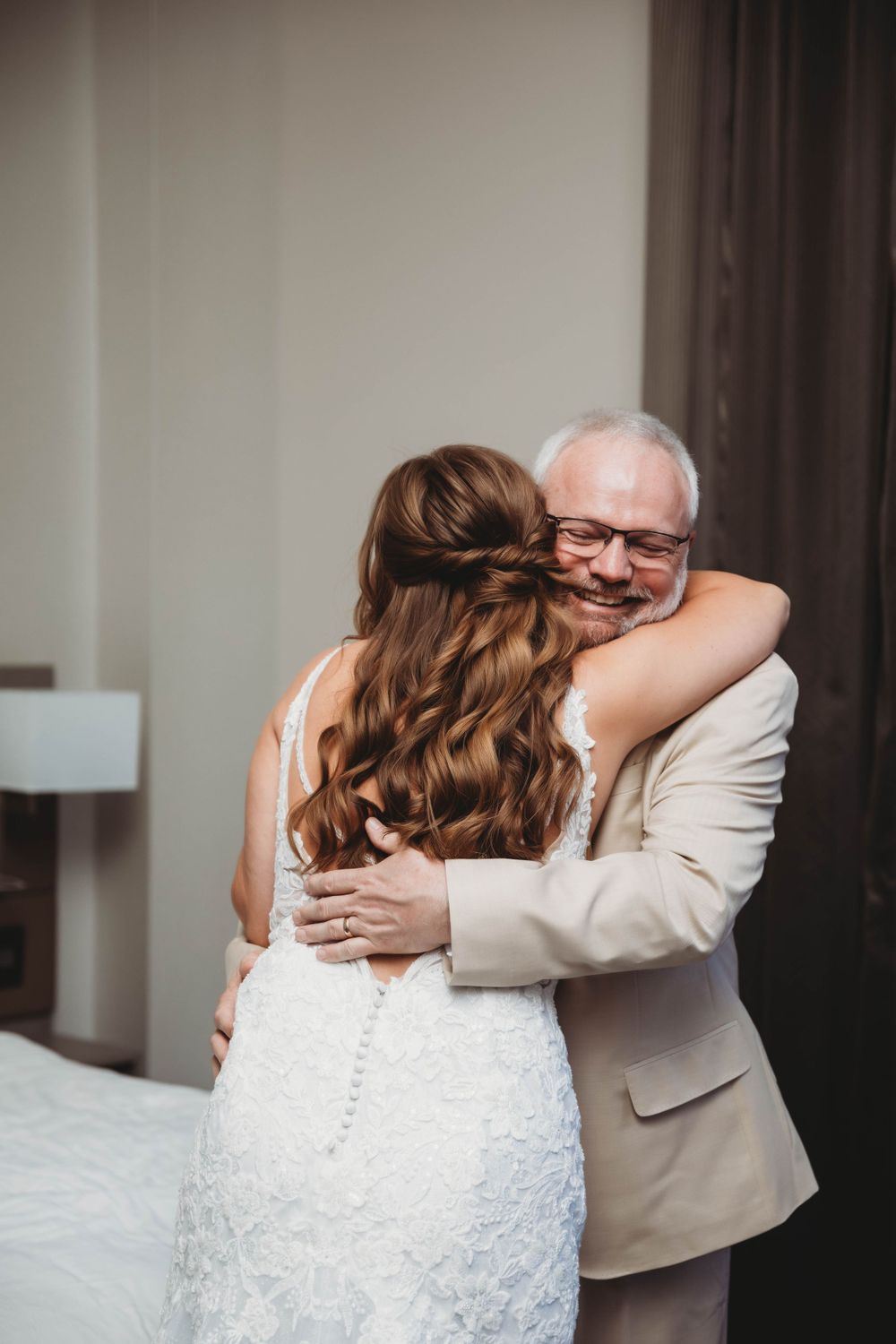 An emotional moment between a bride and a person in a beige suit sharing a heartfelt embrace.