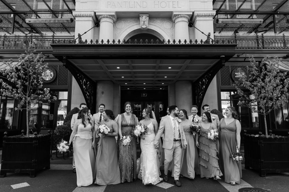 Black and white photo of wedding party lined up under architectural entrance.