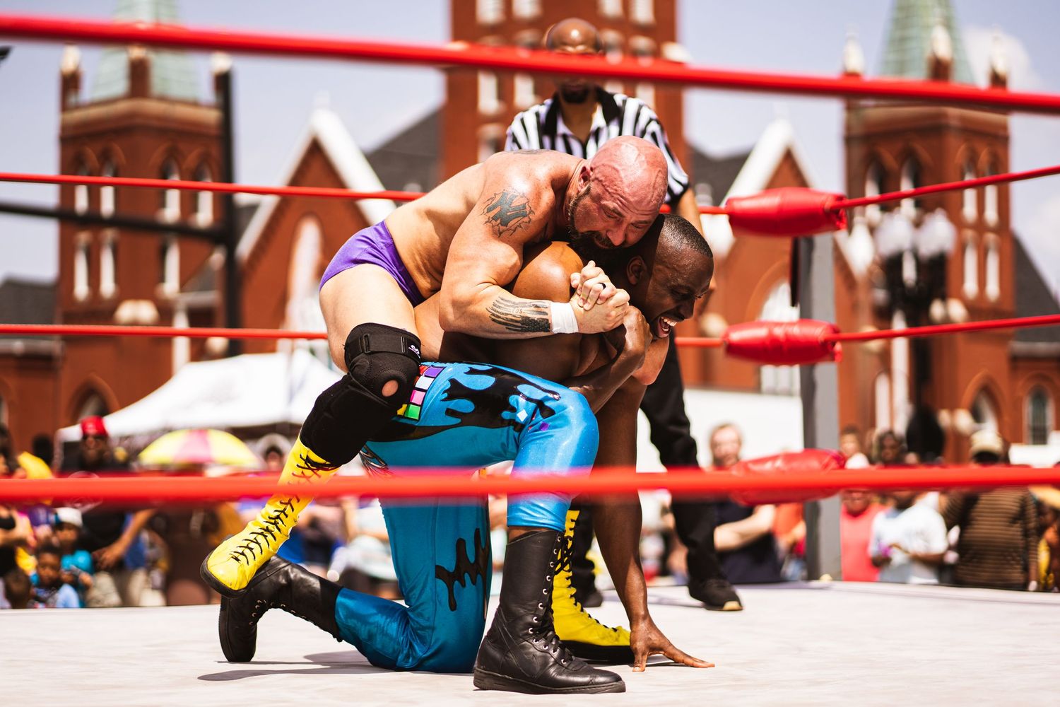 Two wrestlers engaging in dramatic wrestling match on outdoor ring stage.