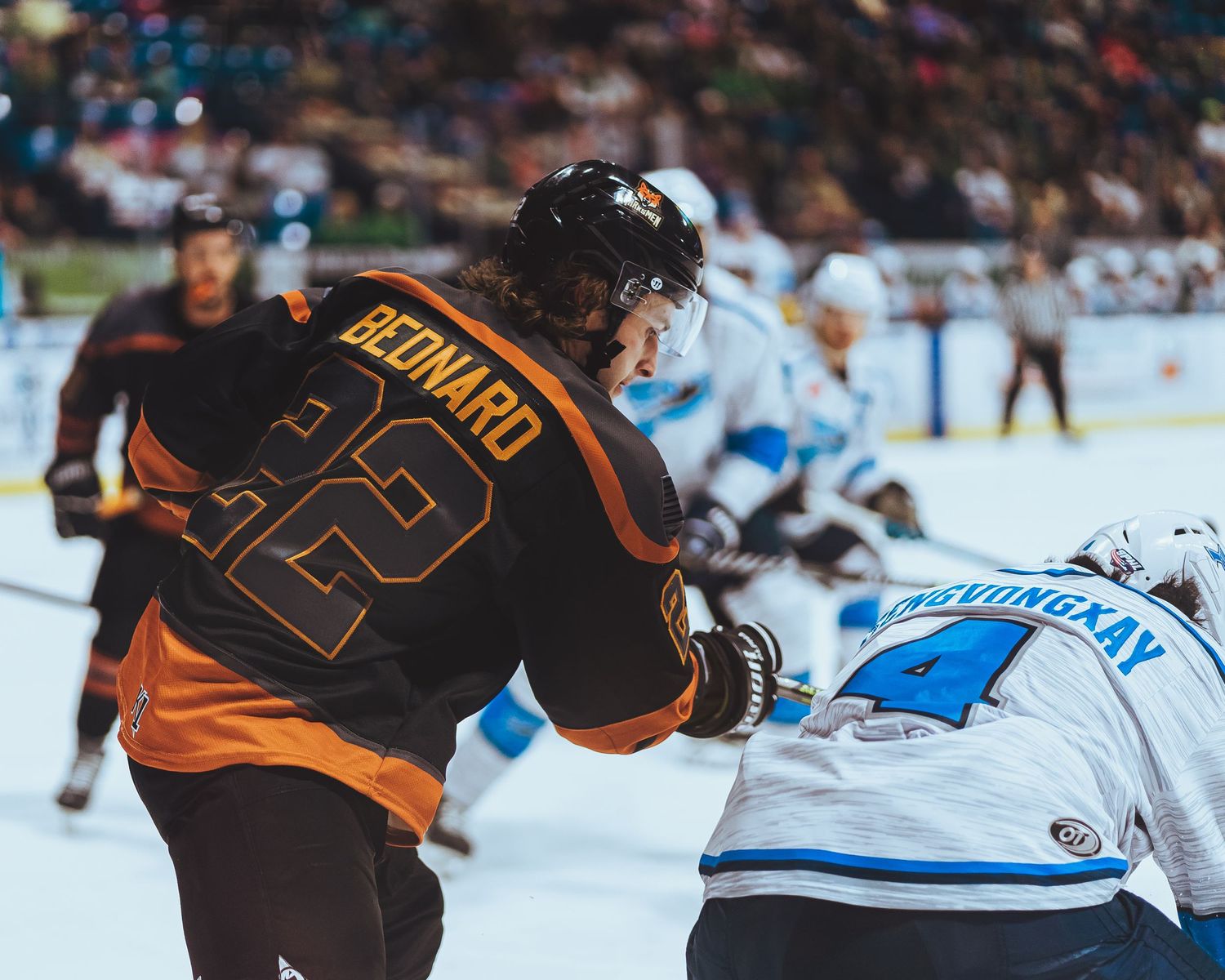Ice hockey player in orange jersey competing during intense game action.