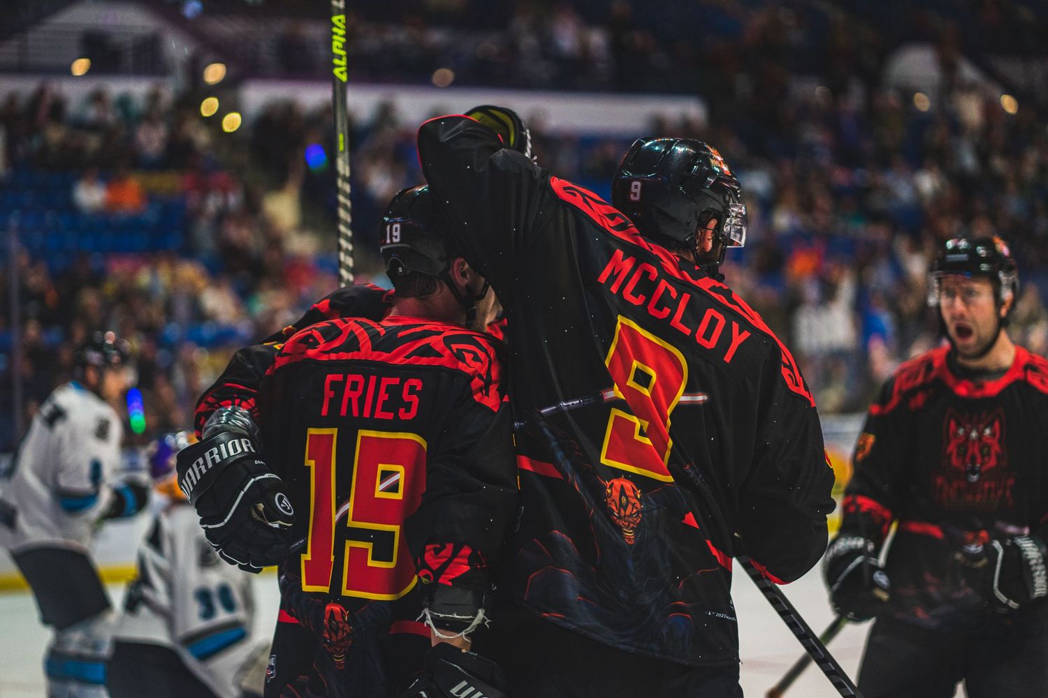 Hockey players wearing red and black jerseys during a competitive match.