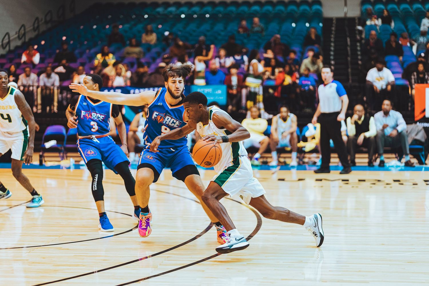 Basketball players in blue and white uniforms competing intensely for ball possession.