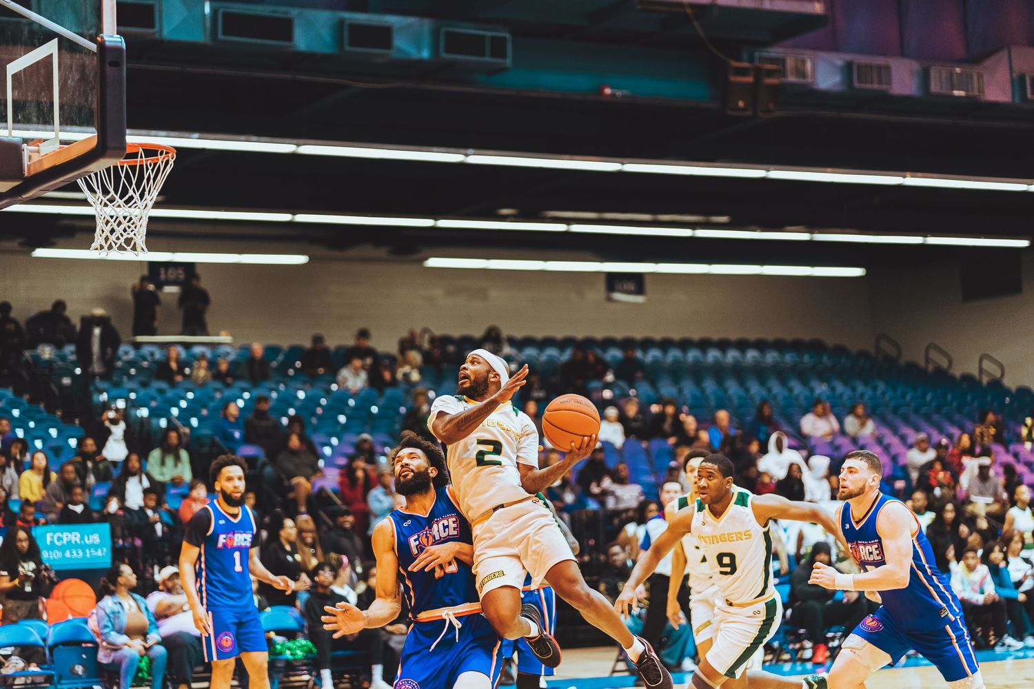 Basketball player leaping for a dunk during an intense game with spectators watching.