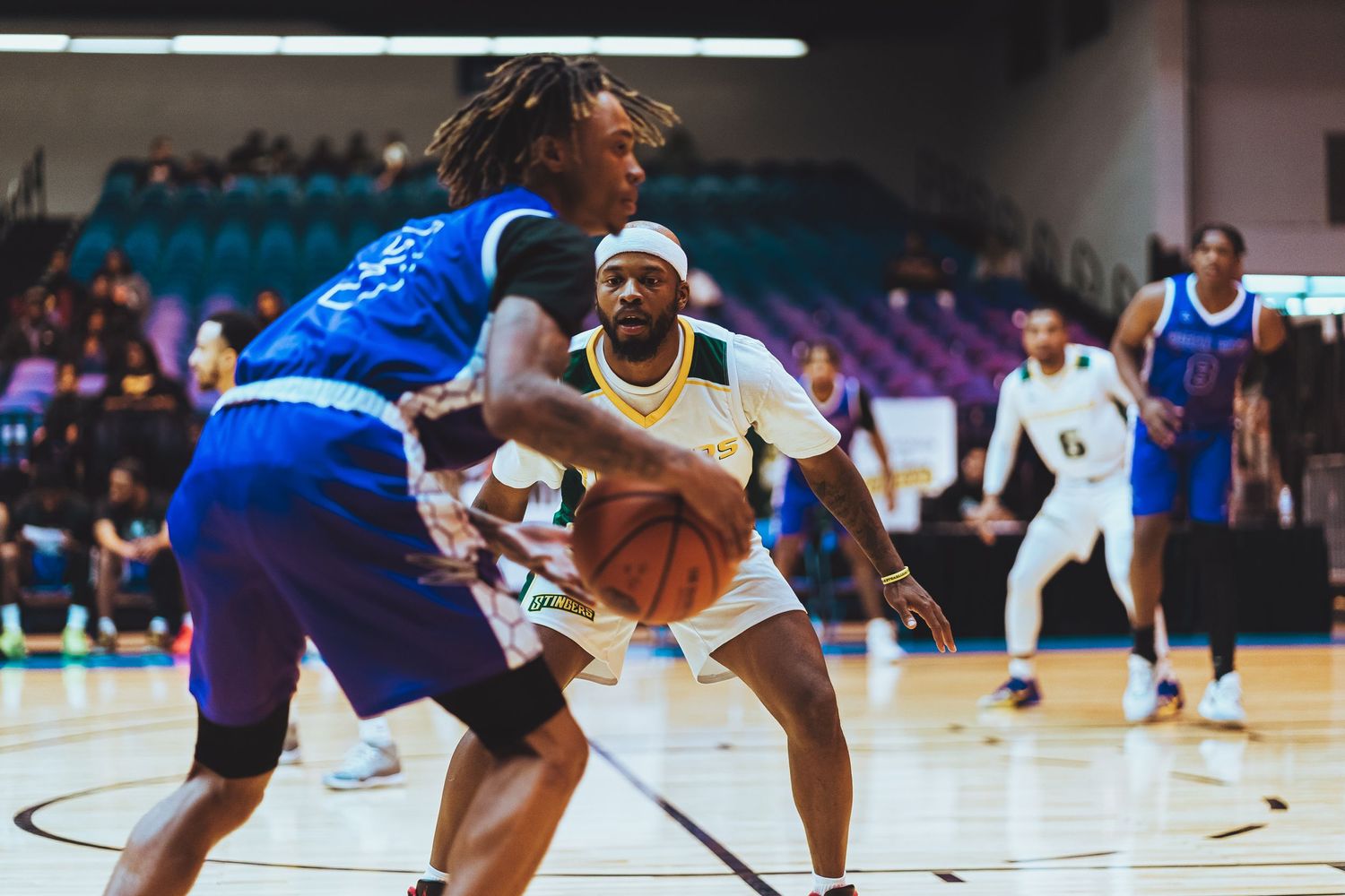 Basketball players from opposing teams compete intensely during game on indoor court.