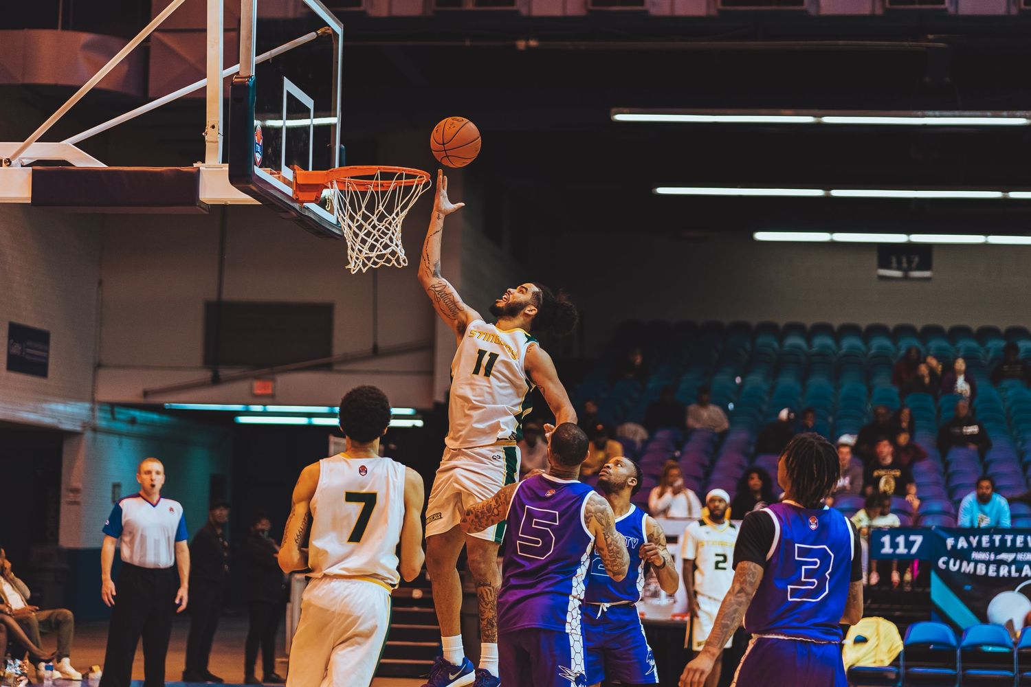 Basketball player leaps high for layup while defenders try to block the shot.