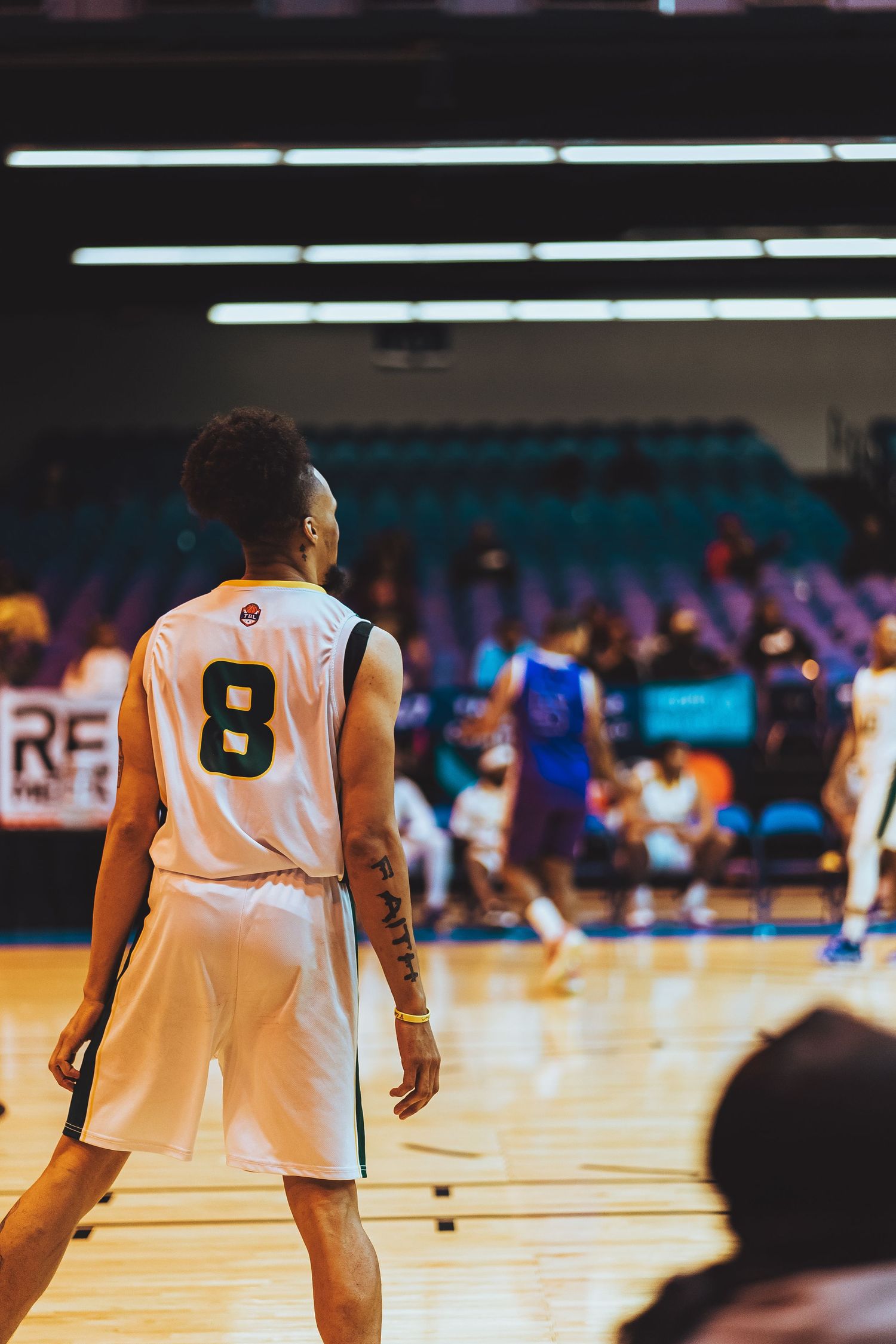 Basketball player in white jersey number 8 stands ready on court during game.