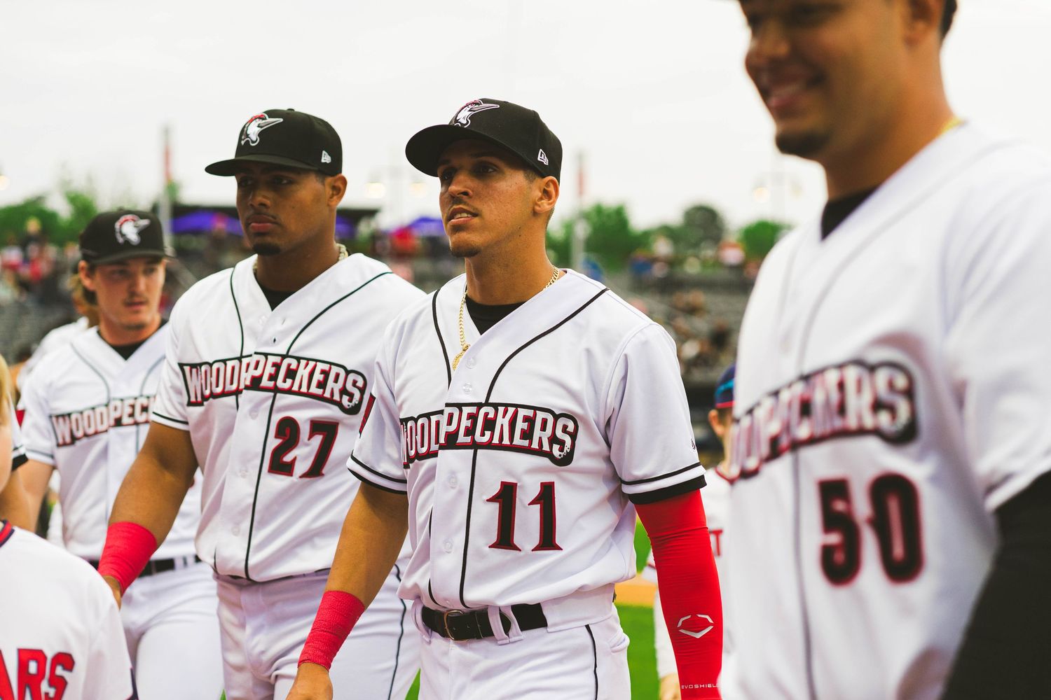 Baseball players in white Roughriders uniforms standing together on the field.