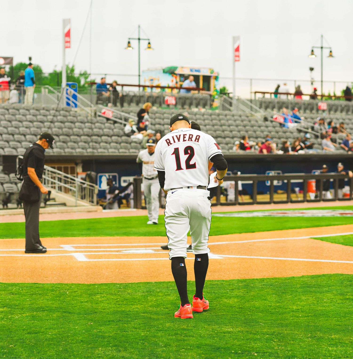 Baseball player wearing jersey number 12 standing at home plate during a minor league game.