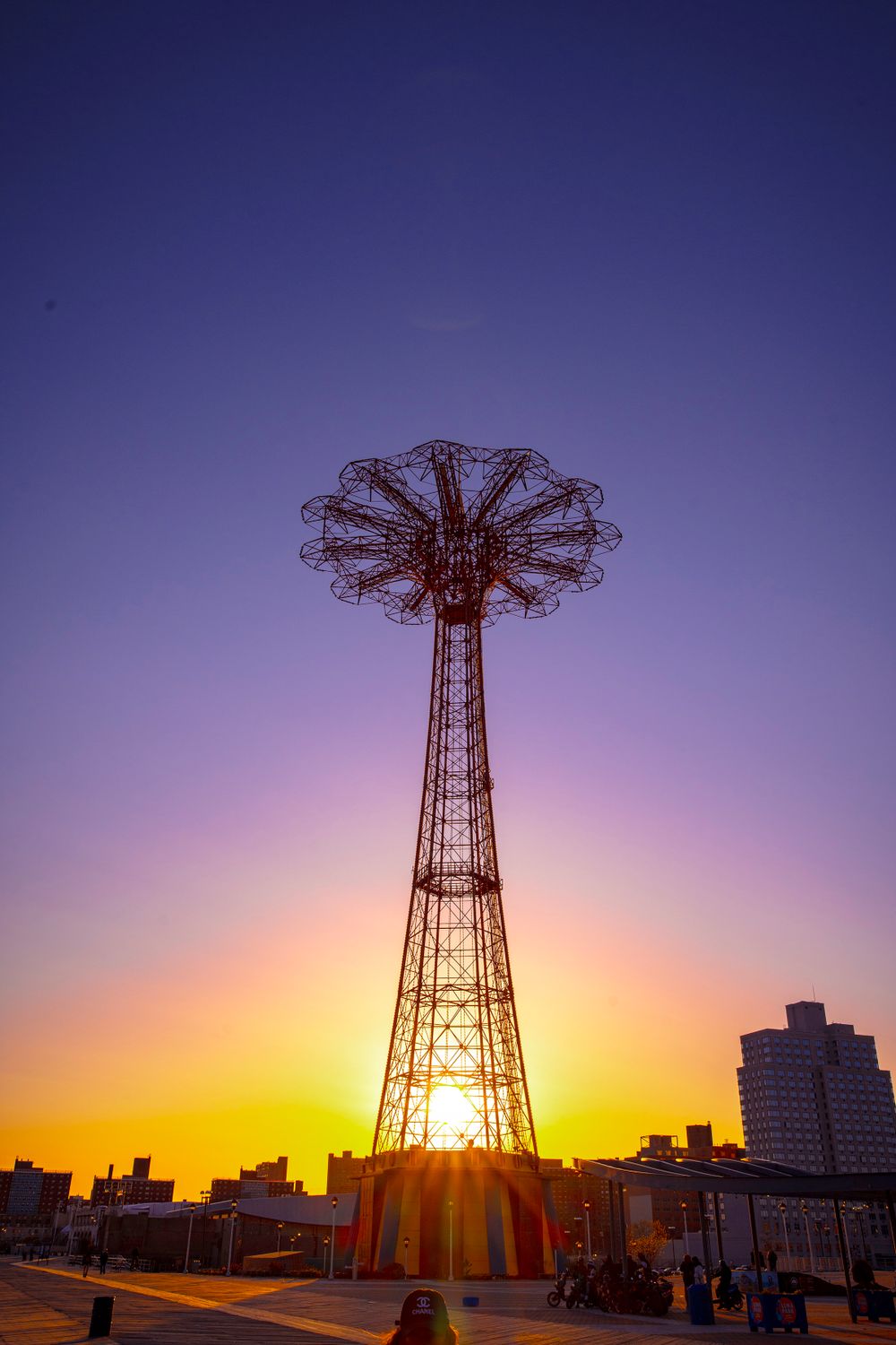 Historic Coney Island Parachute Jump tower glowing against a purple and orange sunset.
