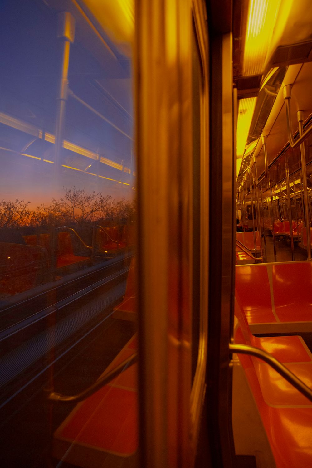 View from inside a subway car at sunset with warm golden light streaming through the windows.