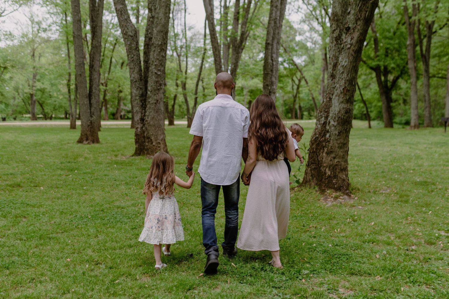 Family walking together through a lush green forest on a spring day.